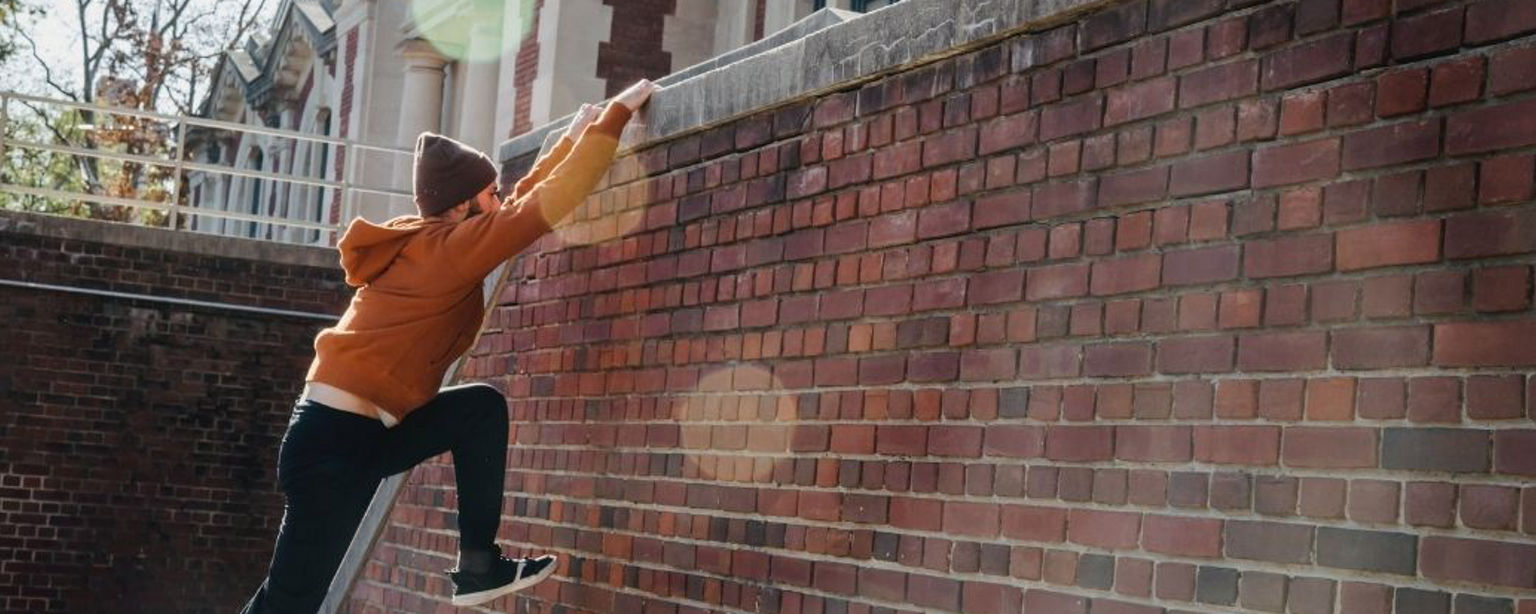 Ein Parkour-Athlet erklimmt eine hohe Mauer vor einem Gebäude